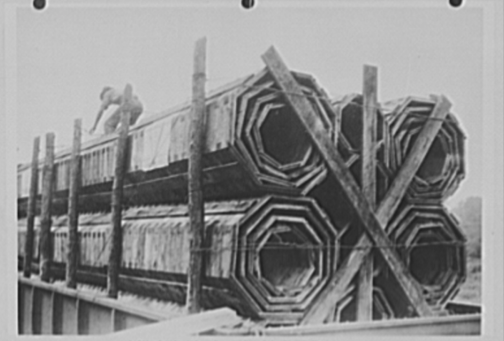A shipment of 1,488 feet of 18-inch, 24-inch, 30-inch and 36-inch wooden pipe on one flat car. Weight 70,020 pounds. An equal footage of reinforced concrete pipe weighs 455,412 pounds, requires over ten cars. About 100,000 feet of these wooden pipes were installed in 1942 in drainage culverts, storm sewers and conduits, under highways and at army camps, naval stations, airfields and ordnance plants